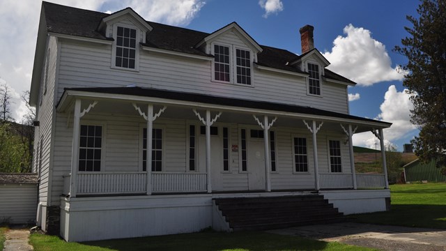 A white two-story building with an outer porch.