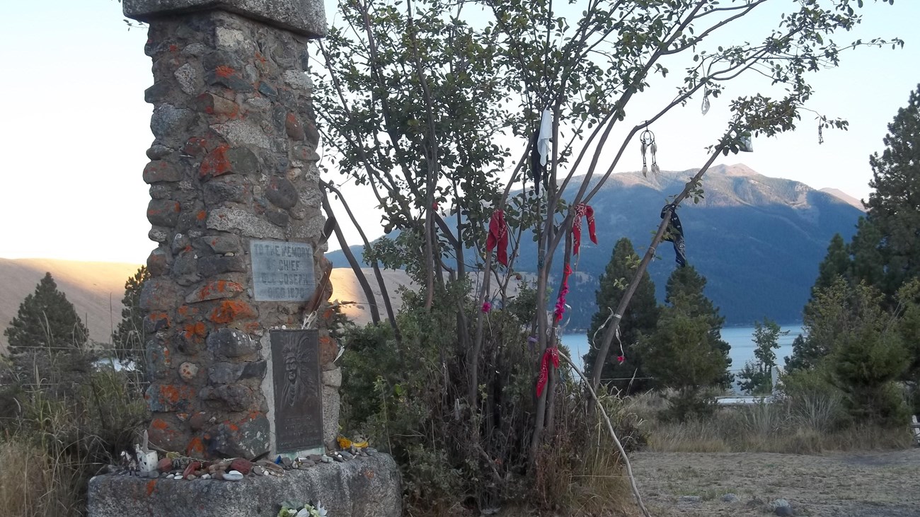 A monument beside a lake as the sun sets.
