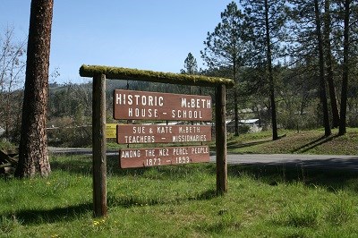 A brown wooden sign with the words 'Historic McBeth House — School.'