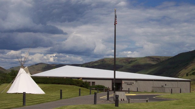 A one-story building with a white tipi and American flag out front.