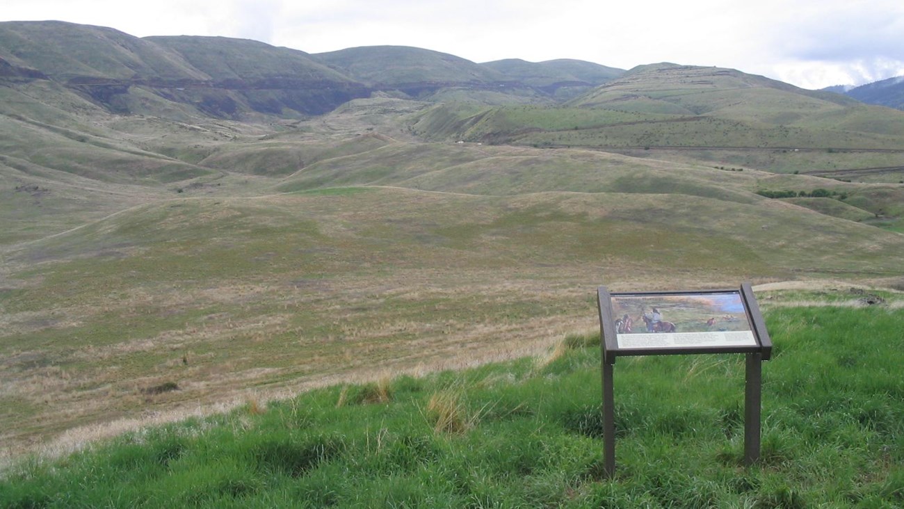 Vista of rolling hills and canyons with an information panel in the foreground.